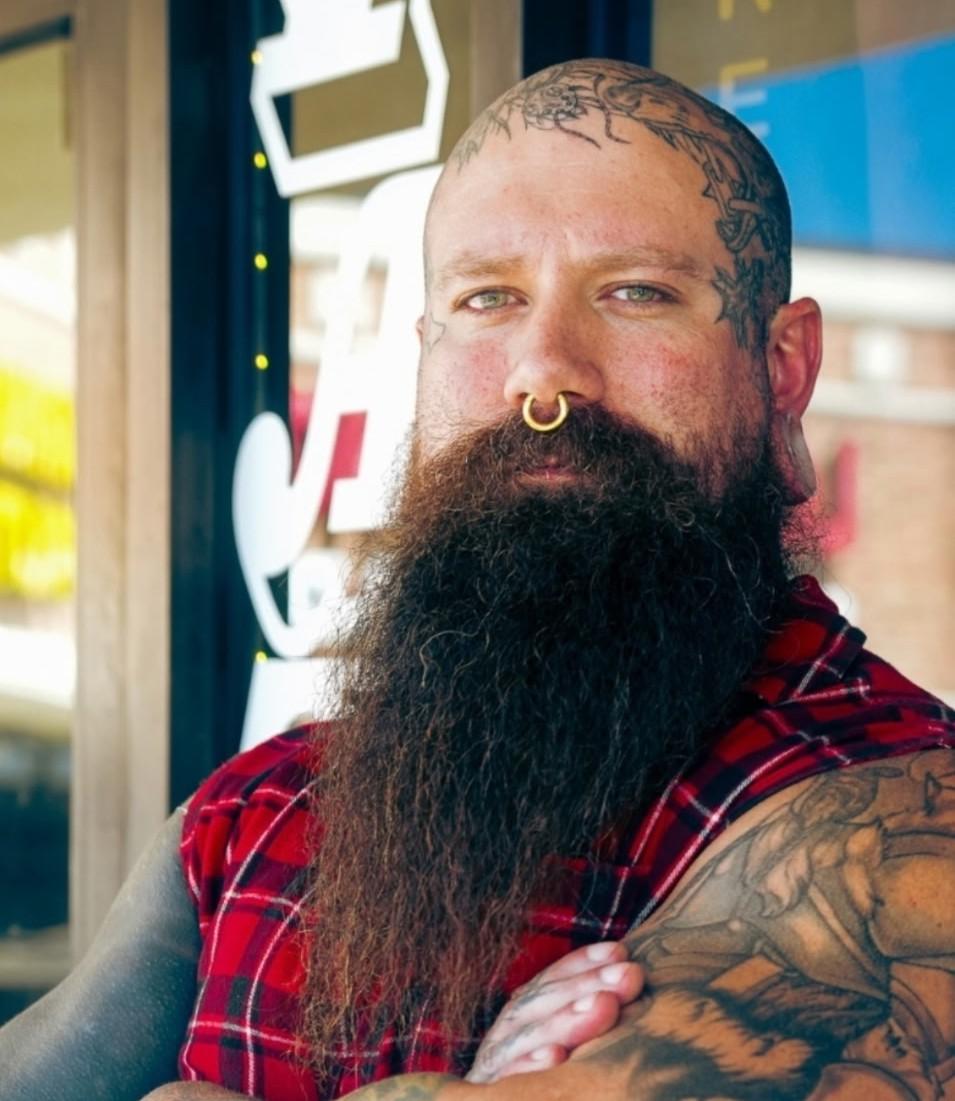 Man with beard and plaid shirt with tattoos name Bryan Rawlings